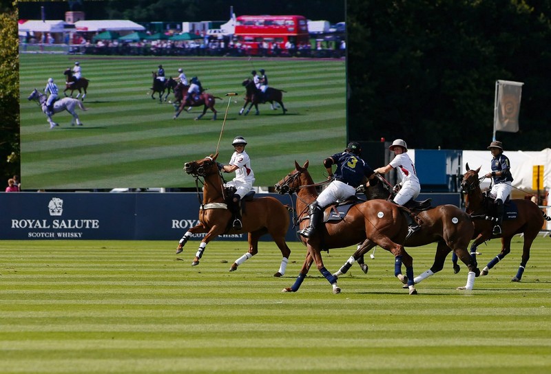 South America (navy) and England fight for the ball during The Royal Salute Coronation Cup at Guards Polo Club in Windsor Great Park-